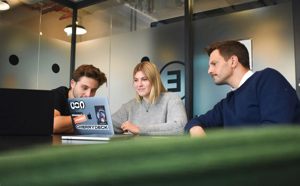 Three colleagues reviewing work on a laptop